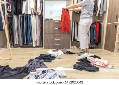 Young Woman Throwing Clothes In Walk In Closet. Mess In Wardrobe And Dressing Room