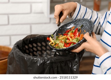 Young woman throwing organic food into trash bin in kitchen, closeup. Waste recycling concept - Powered by Shutterstock