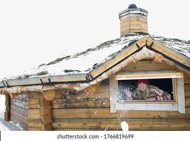 A Young Woman Throwing A Snowball From The Window Of A Log Cabin