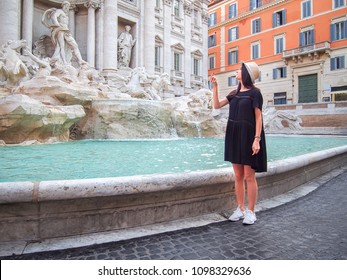 Young Woman Throws A Coin In The Trevi Fountain In Rome, Italy