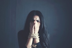 Young woman in red dress with tied hands behind her back. Indoor photo ...