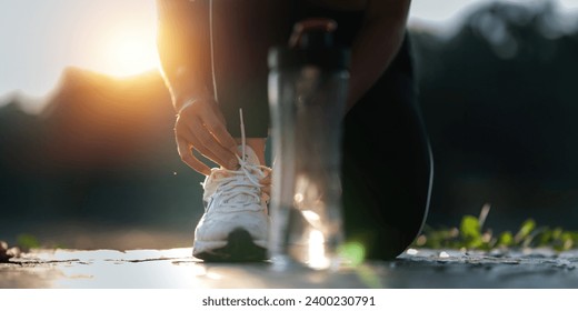 Young woman ties shoelaces while stretching stretch during stretching exercise outdoors in the park - Powered by Shutterstock