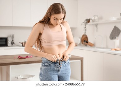 Young woman in tight jeans at home. Weight gain concept - Powered by Shutterstock