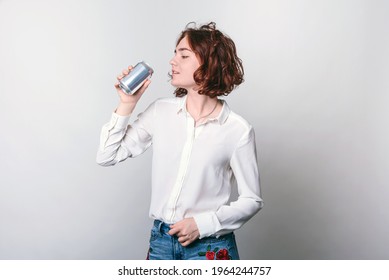 A Young Woman With A Tin Can, A Metal Soda Can, Or A Beer Can In Front. Cylindrical Aluminum Cans, Bottles Of Cold Drinks, A Woman Holding A Metal Can.