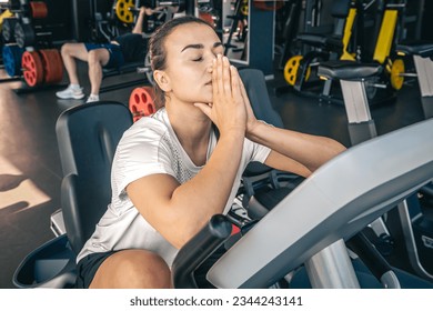 A young woman tired after intense workout on the exercise bike at the gym. - Powered by Shutterstock