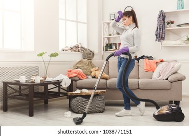 Young Woman Tired Of Spring Cleaning House, Washing Floor With Vacuum Cleaner In Messy Room, Copy Space