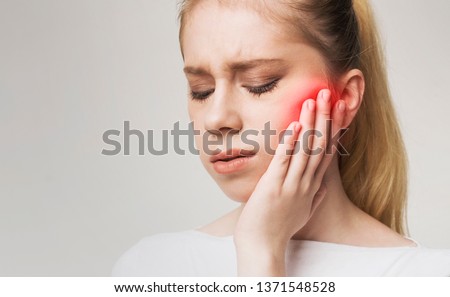 Young woman touching her cheek, having strong toothache and suffering from pain, empty space