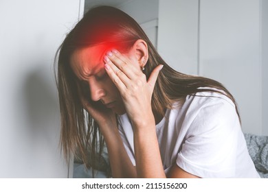 Young woman touching her temples and suffering from head pain, headache or migraine - Shutterstock ID 2115156200