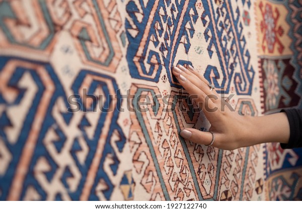 Young woman touching the traditional turkish\
carpet.Traditional culture\
products.