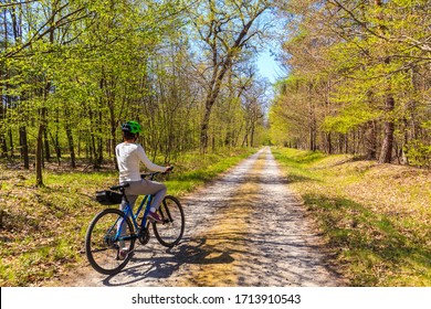 Young woman tourist cyclist on road in forest on sunny spring day in Puszcza Niepolomicka near Krakow city, Poland - Powered by Shutterstock