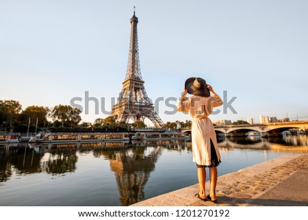 Young woman tourist enjoying landscape view on the Eiffel tower with beautiful reflection on the water during the mornign light in Paris