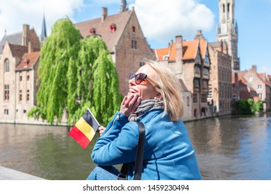Young woman tourist with the flag of Belgium in the hands is enjoying the views of the city in the historic center of Bruges near the famous viewport. Travel to Belgium.