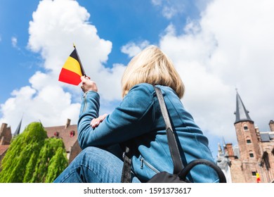 Young woman tourist with the flag of Belgium in the hands is enjoying the views of the city in the historic center of Bruges near the famous viewport. Travel to Belgium.