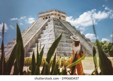 A young woman tourist in a hat stands against the background of the pyramid of Kukulcan in the ancient Mexican city of Chichen Itza. Travel concept.Mayan pyramids in Yucatan, Mexico 