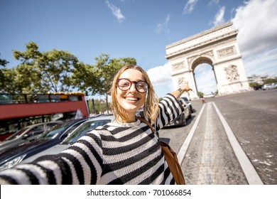 Young Woman Tourist Making Selfie Portrait With Famous Triumphal Arch On The Background In Paris