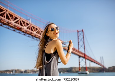 Young woman tourist photographing famous iron bridge in Lisbon city, Portugal - Powered by Shutterstock