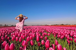 Junge Touristinnen In Rosafarbenem Kleid Und Strohhut Auf Blühendem Tulpenfeld. Frühlingszeit