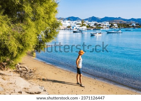 Young woman tourist standing on beach in Pollonia port, Milos island, Cyclades, Greece