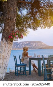 Junge Touristinnen aus Strohhut, die in einem Café mit Meerblick auf Ermioni, Griechenland