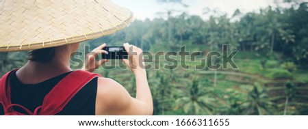 Young woman tourist taking picture using her smartphone camera in beautiful green jungles. Wide screen