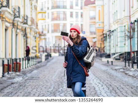 Young woman tourist taking selfie using smartphone, on the city street.