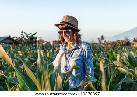Young woman tourist traveler with straw hat on cornfield on a volcano Agung background at sunset time. Bali island. Mount Agung.
