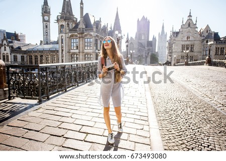 Young woman tourist walking the bridge in the old town of Gent city durnig the sunrise in Belgium