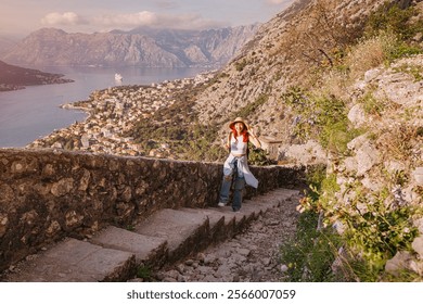 Young woman tourist walking up cobblestone path in historic town of Kotor, Montenegro, exploring ancient fort on a mountain - Powered by Shutterstock