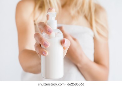 Young woman in towel after shower using body cream. Skin care.