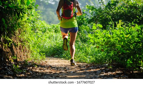 Young Woman Trail Runner Running In Tropical Forest 