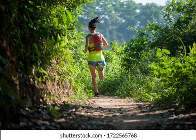 Young Woman Trail Runner Running In Sunrise Tropical Forest