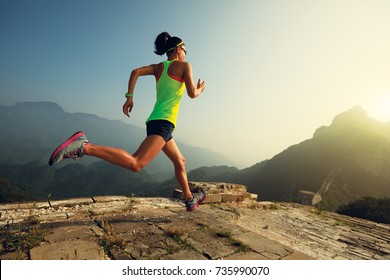 Young woman trail runner running at great wall on the top of mountain