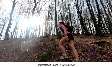 Young Woman Trail Running In The Mountains With Her Dog