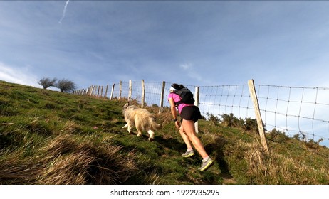 Young Woman Trail Running In The Mountains With Her Dog