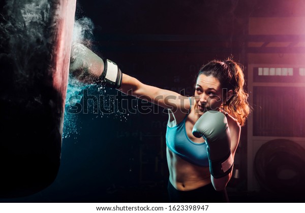young woman\
training boxing in the punching bag - sport, self defense, boxing\
and training concepts - swing\
boxing
