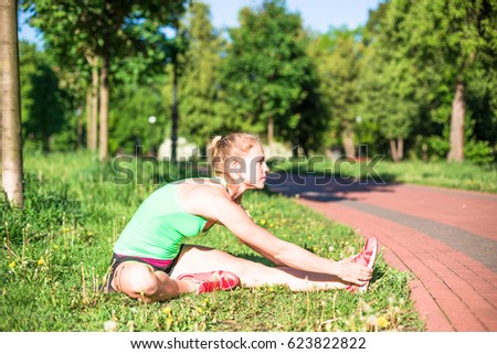 Young woman training in city park at summer day