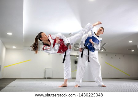 Young woman training martial art of taekwondo with her coach, sportsmanship concept 