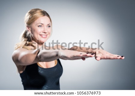 Close up side view profile portrait of one young athletic woman shadow boxing in sportswear in gym over dark background, looking away