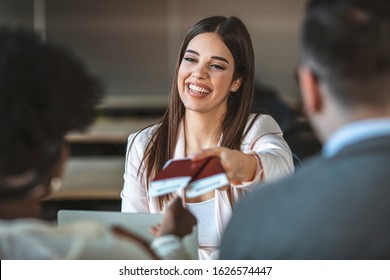 Young woman travel agent with flight tickets in hands. Travel agent giving tickets and passport to tourist. Young couple in a tour agency communication with a travel agent travelling concept 