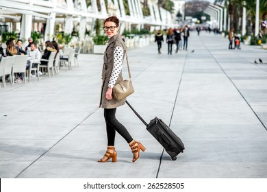 Young Woman With Travel Bag And Phone Walking At The Promenade In Split Cty In Croatia