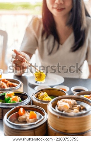Young woman traveler eating traditional Chinese Dim Sum at restaurant