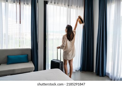 Young Woman Traveler With Luggage Looking At View In Hotel Room On Summer Vacation