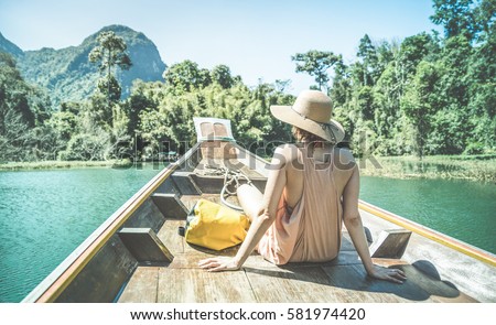 Young woman traveler on longtail boat trip at island hopping in Cheow Lan Lake - Wanderlust and travel concept with adventure girl tourist wanderer on excursion in Thailand - Retro turquoise filter