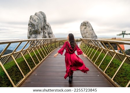 Young woman traveler in red dress enjoying at Golden Bridge in Bana hills, Danang Vietnam, Travel lifestyle concept