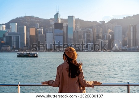 Young woman traveler relaxing and enjoying the sunset atmosphere at Victoria harbour in Hong Kong