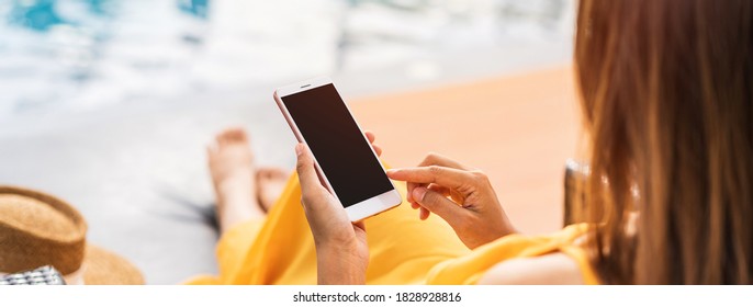 Young Woman Traveler Relaxing And Using A Mobile Phone By A Hotel Pool While Traveling For Summer Vacation