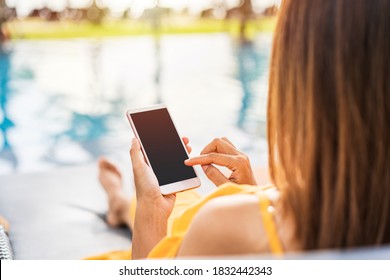 Young Woman Traveler Relaxing And Using A Mobile Phone By A Hotel Pool While Traveling For Summer Vacation