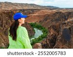 Young woman traveler standing against the Black Canyon landscape. The Black Canyon is part of the Charyn Canyon and Charyn National Park. Located in the Almaty region in south-eastern Kazakhstan