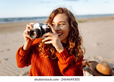 Young woman traveler is taking pictures of nature on retro camera in picnic at the beach. Trip, photography or girl with nature. - Powered by Shutterstock