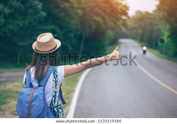 Young woman traveler thumbs up need\
help on the road side after car engine broken\
down